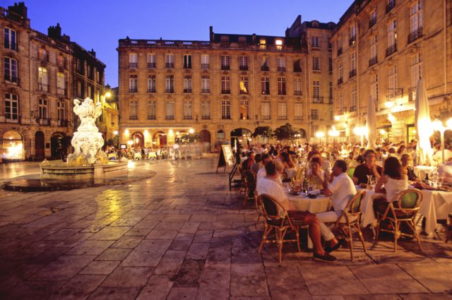 IMAGE: Photo showing a square in Bordeaux at dusk with people having dinner